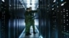 GENERIC – In Data Center Two Military Men Work with Open Server Rack Cabinet. One Holds Military Edition Laptop.